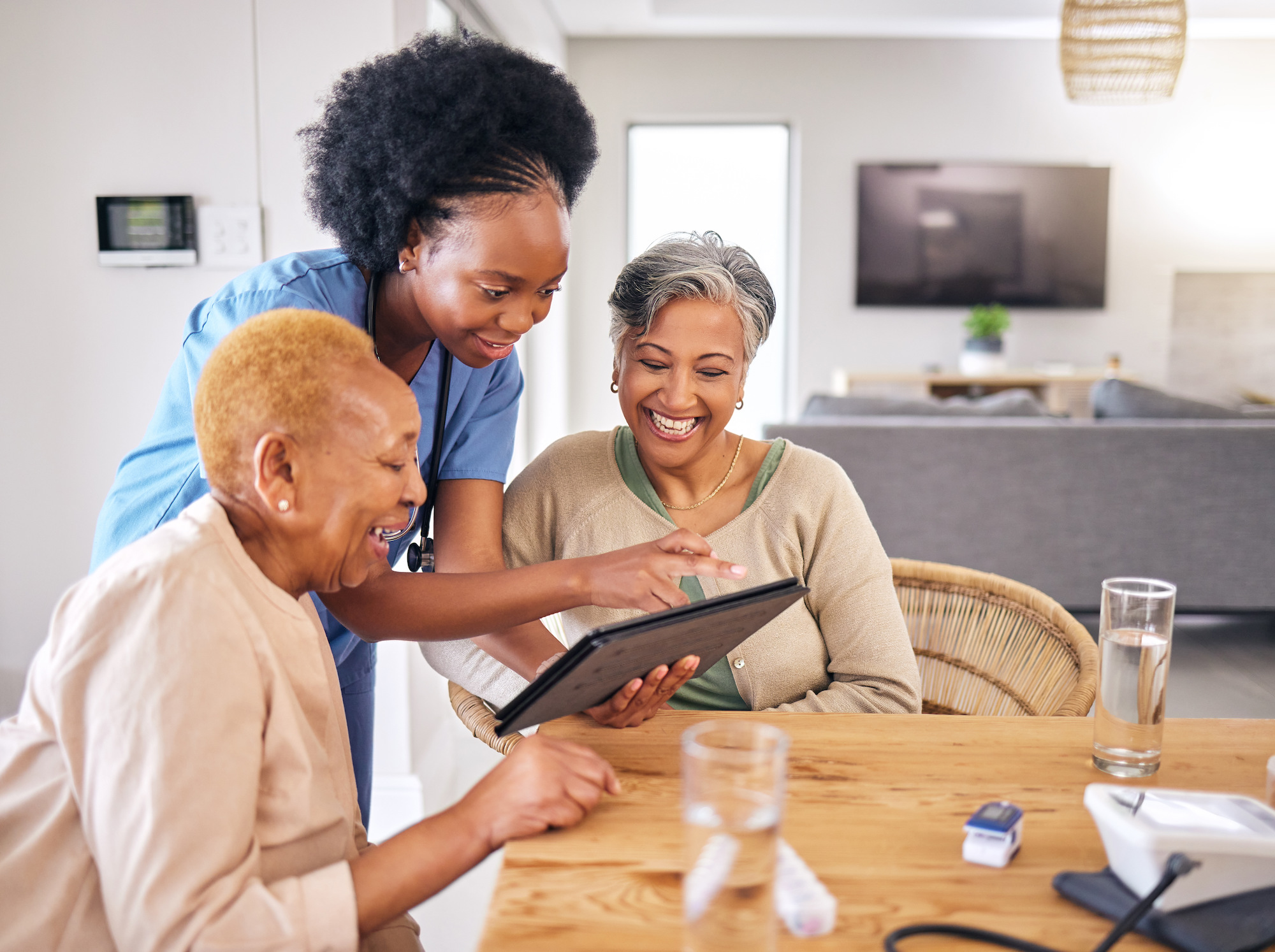 nurse showing two older ladies something in an assisted living center